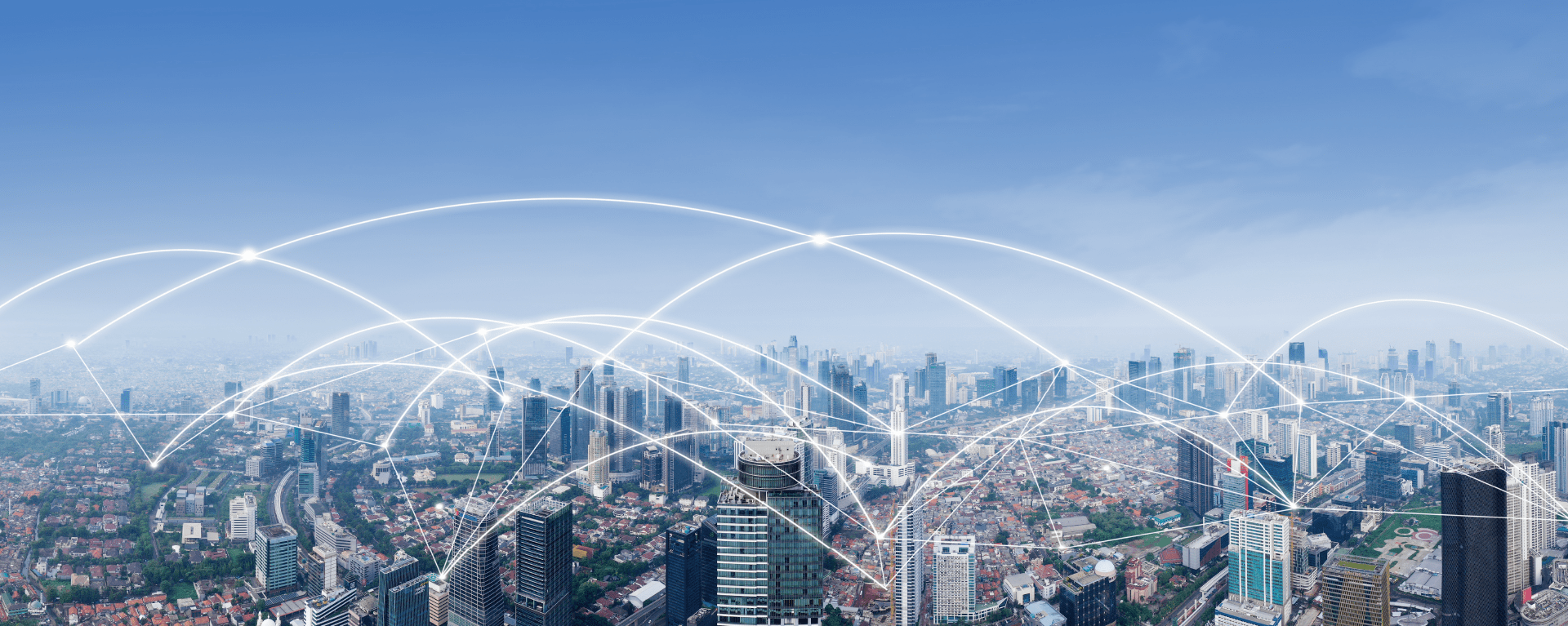 A wide aerial view of a metropolitan city with many skyscrapers is overlaid with a white graphic representing a network connecting the buildings to one another